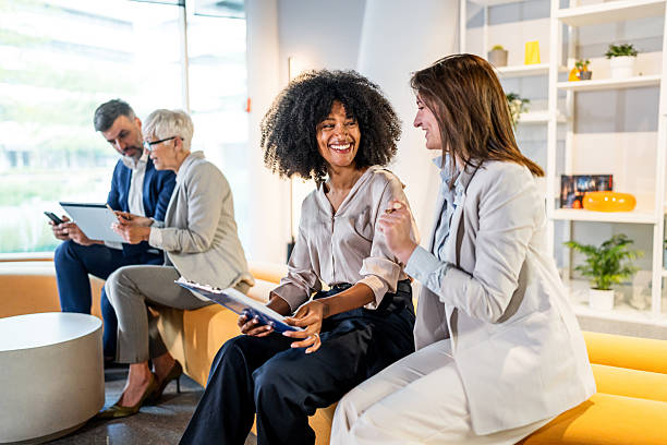 istock Businesswomen collaborating on project in modern office lobby 2218631415
