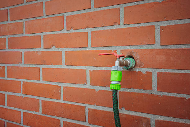 Fountain in classic brick wall with attached water hose.