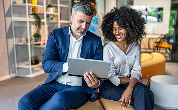istock Smiling business people using digital tablet in modern office lobby 2218632010