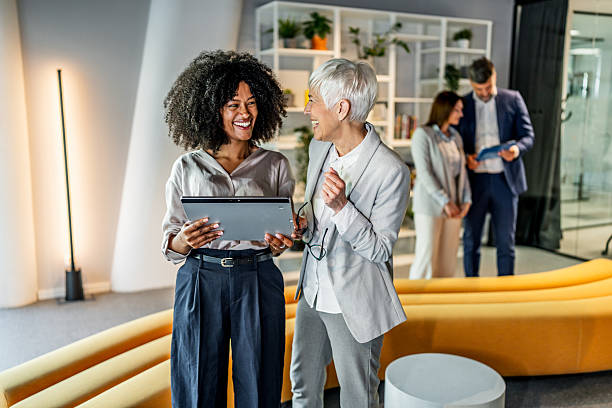 istock Businesswomen using digital tablet in modern office lobby with coworkers 2218632616