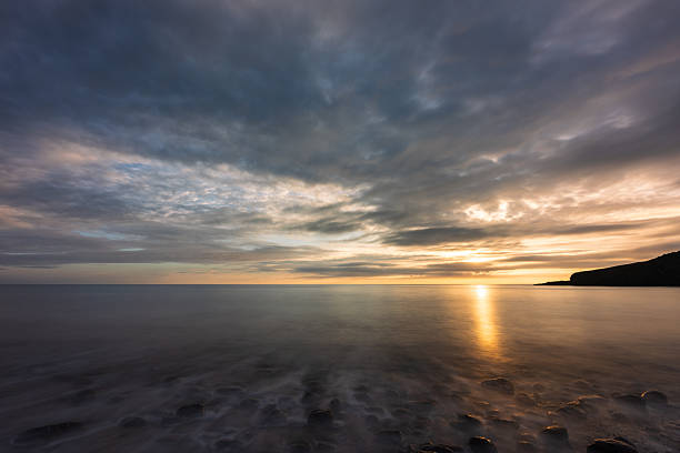 Funky clouds, warm light and soft water on the beach
