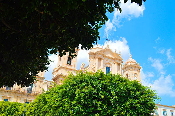 A majestic view of the Cathedral of Noto, a Baroque masterpiece in southeastern Sicily, captured with warm golden tones and dramatic architectural detail against a vivid sky.