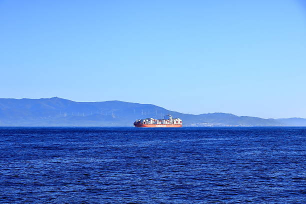 Strait of Gibraltar - February 17 2025: a container ship with spanish mountains in background