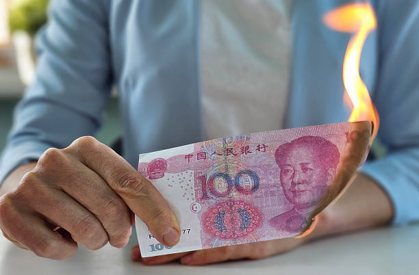 Person holding a burning Chinese hundred yuan note