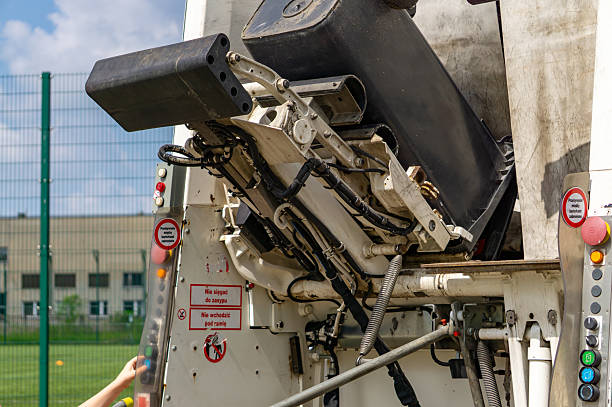 istock Garbage truck lifting mechanism in action while emptying a bin. Visible hydraulic cylinders, control panel, and safety warnings 2218635288