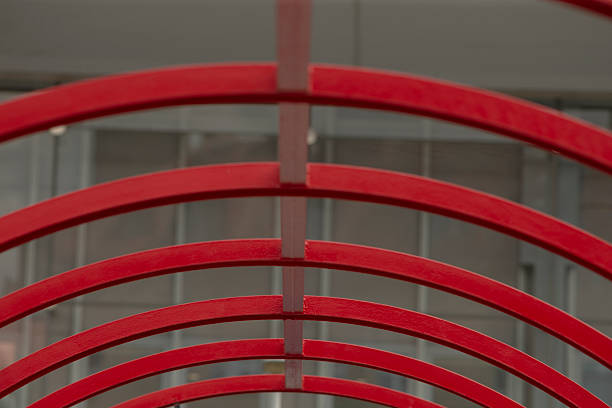 The image showcases bold red arches in a contemporary scene, with elegantly overlapping curves set against a transparent glass backdrop that enhances depth and visual interest