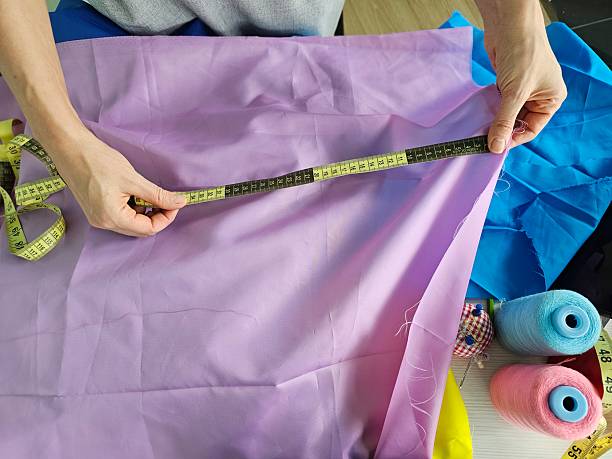 Measuring fabric for sewing project with colorful textiles and thread spools in a creative workspace
