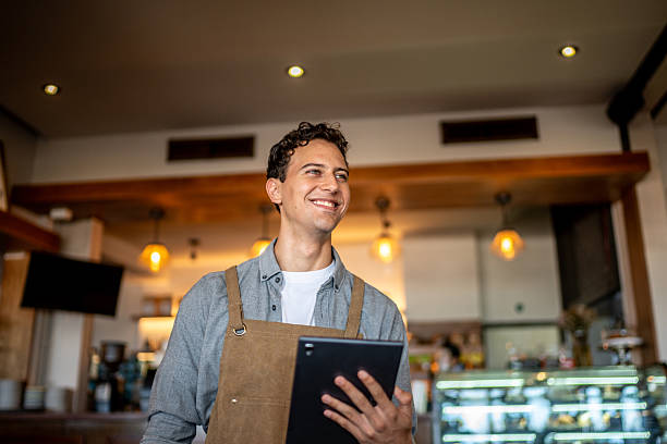 istock Young waiter contemplating and using digital tablet at coffee shop 2218637701
