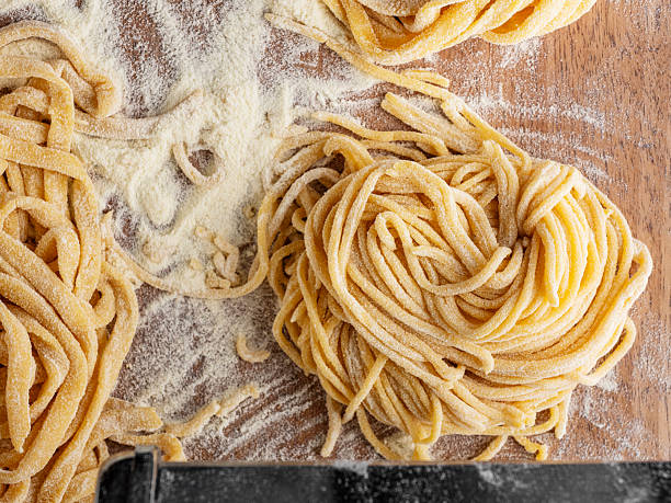 istock Fresh raw uncooked pasta.Raw tagliatelle macaroni nest. Machine for making homemade pasta.Homemade pasta on a wooden background. Tagliatelle italian fresh pasta background. 2218643767