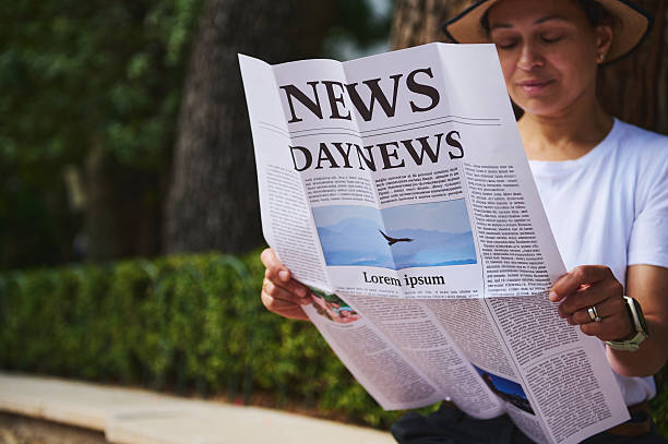 istock Person Reading a Newspaper Outdoors in a Park Setting with Greenery 2218646669
