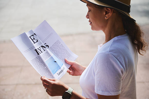istock Woman Reading a Folded Newspaper Outdoors on a Sunny Day 2218646670