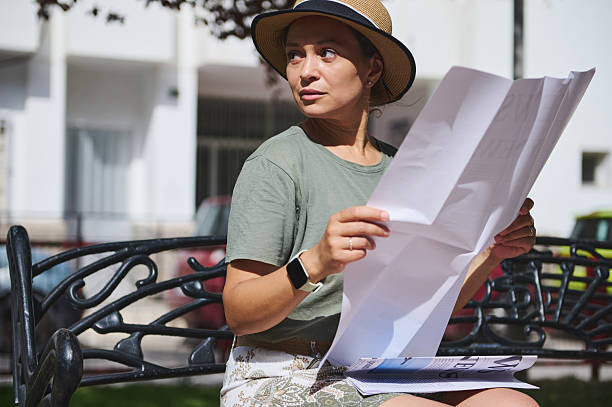 istock Woman Reading a Newspaper on a Park Bench on a Sunny Day 2218646741