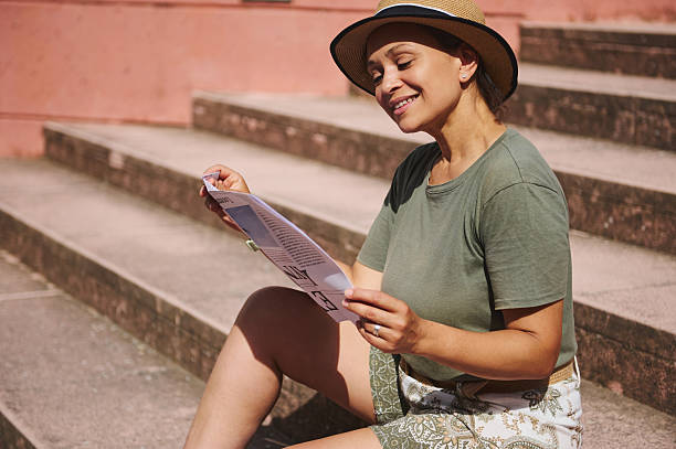 istock Woman Relaxing Outdoors, Smiling While Reading a Paper Under the Sun 2218647724