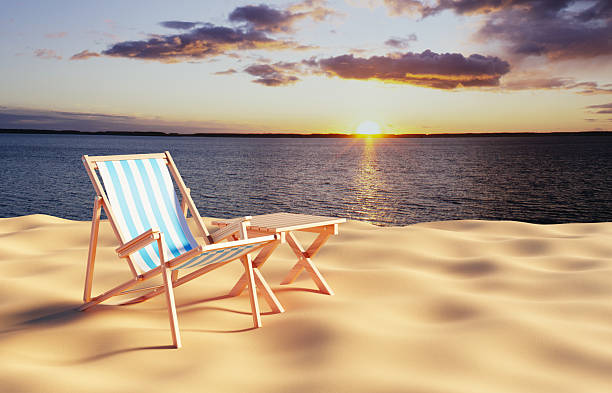 Deck chair with table on the beach against the sunset. 3d-rendering