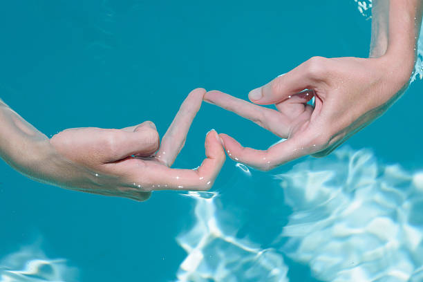 istock Hands creating a heart shape underwater in a clear swimming pool surrounded by sunlight reflecting off the surface. 2218651832