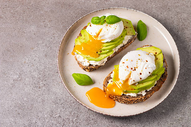 istock Toast with avocado, soft cream cheese, rye bread and poached Egg. Wholemeal open sandwich for healthy breakfast concept 2218651897