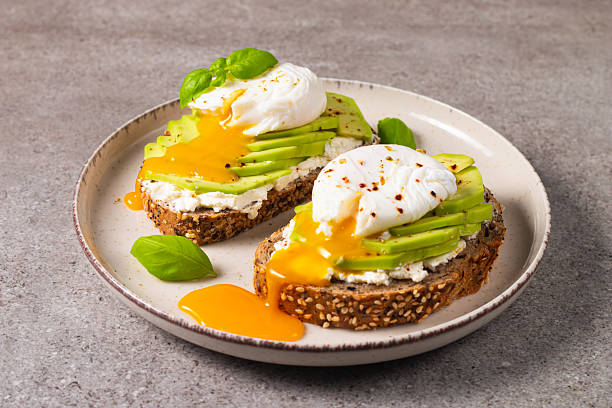 istock Toast with avocado, soft cream cheese, rye bread and poached Egg. Wholemeal open sandwich for healthy breakfast concept 2218651928