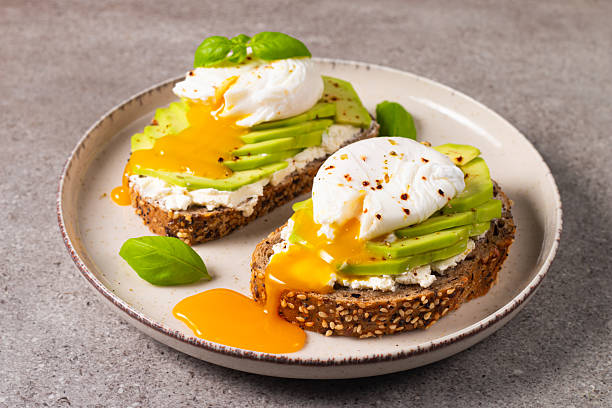 istock Toast with avocado, soft cream cheese, rye bread and poached Egg. Wholemeal open sandwich for healthy breakfast concept 2218651929