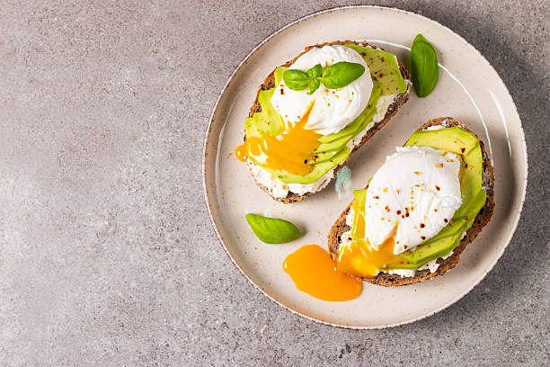 istock Toast with avocado, soft cream cheese, rye bread and poached Egg. Wholemeal open sandwich for healthy breakfast concept 2218651930