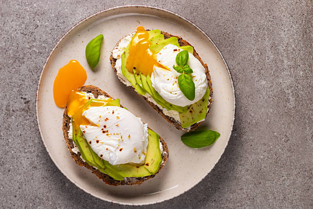 istock Toast with avocado, soft cream cheese, rye bread and poached Egg. Wholemeal open sandwich for healthy breakfast concept 2218652059