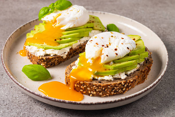 istock Toast with avocado, soft cream cheese, rye bread and poached Egg. Wholemeal open sandwich for healthy breakfast concept 2218652060