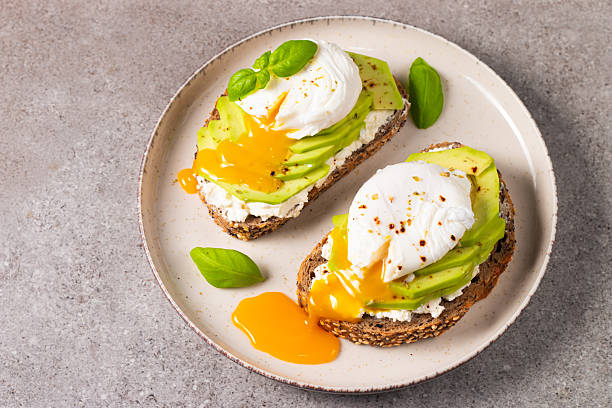 istock Toast with avocado, soft cream cheese, rye bread and poached Egg. Wholemeal open sandwich for healthy breakfast concept 2218652061
