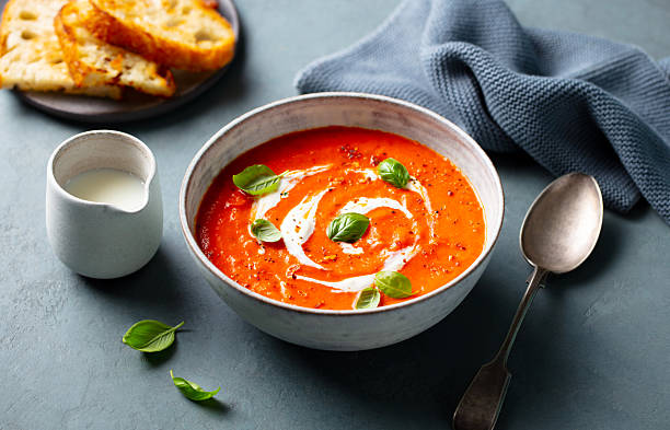 istock Tomato soup with cream and basil leaf in a white bowl on grey background. Close up. 2218652087