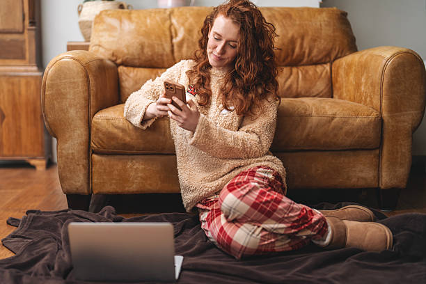 istock Relaxing at home while checking messages on a smartphone in cozy attire and enjoying a comfortable atmosphere on a soft rug in a living room space 2218653364