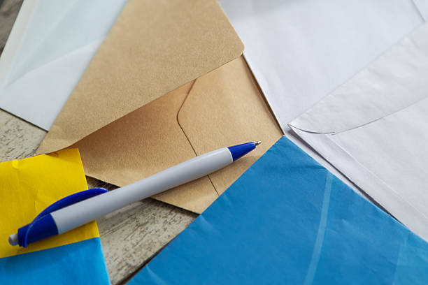 A simple pen against the background of various mail envelopes close-up, mail and dispatch, confidential messages, personal and business correspondence.