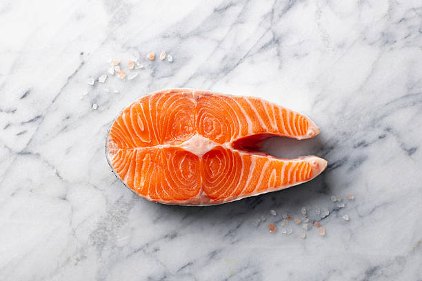 Fresh salmon steak on a marble table is ideal for cooking according to a delicious and healthy recipe. Top view.