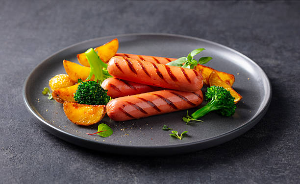 Grilled Sausages with Potatoes and broccoli. Grey background. Close up.