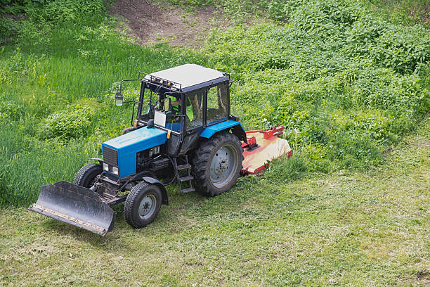 istock Tractor with lawn mower during lawn mowing, machine for cleaning grass, mowing grass and weeds in the field, tractor removes sprouted green grass 2218655465