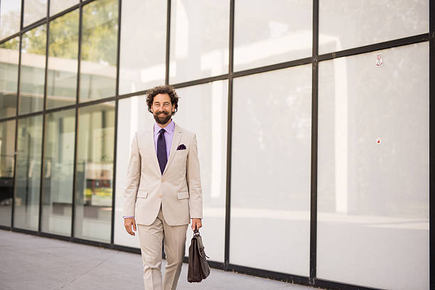 istock Smiling businessman walking outside office building with briefcase 2218655622