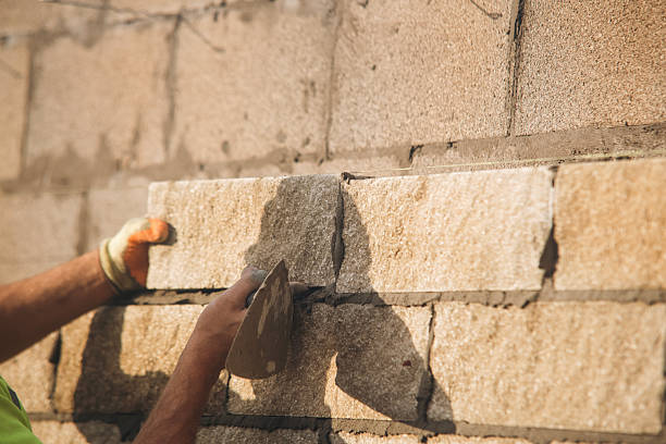 istock Close-up of Bricklayer constructing stone wall using stone blocks, cement mortar mix and trowel 2218655929