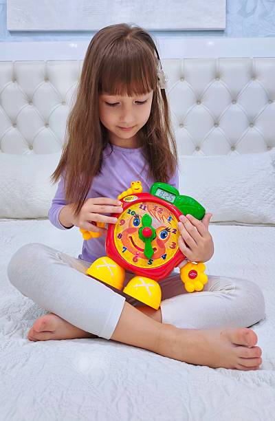 Little girl learning clock by toy . High quality photo