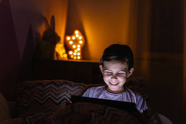 istock Young Girl Using a Tablet in Bed During the Evening 2218660968