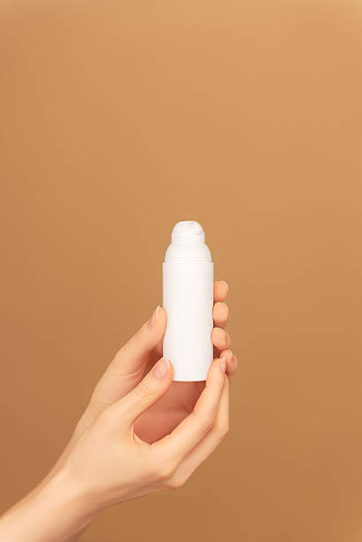 istock Female hands holding white bottle jar with moisturizing cream on beige backdrop 2218660981