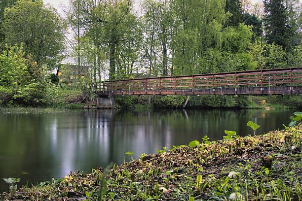 istock Tranquil Wooden Bridge Over Calm River in Spring 2218662110
