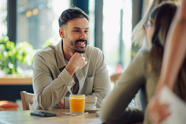 istock Young man enjoying conversation with friends at cafe 2218668756