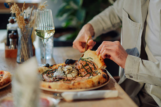 istock Man eating gourmet pizza with wine in restaurant 2218668826