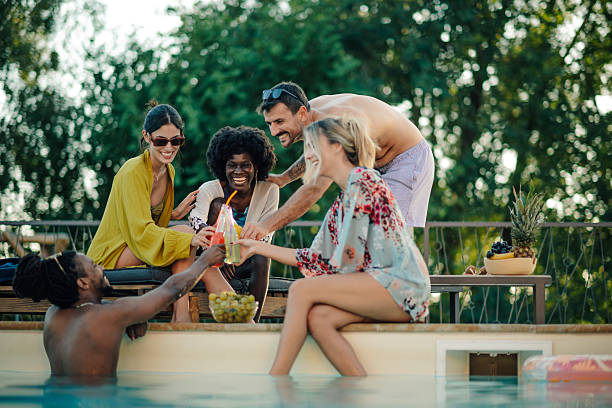 istock Friends toasting drinks at the poolside during summer vacation 2218670027