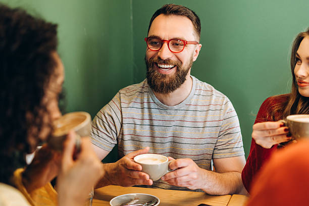 istock Smiling bearded man enjoying coffee break with friends in cafe 2218670152