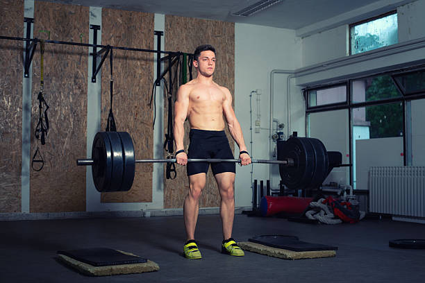 Strong athletic man exercising strength with weights during sports training in a sports gym.