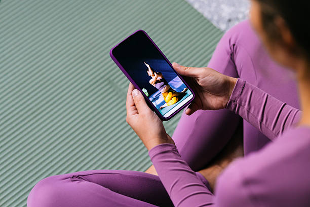 Woman Watching Yoga Tutorial on Smartphone During Home Workout on a Yoga Mat