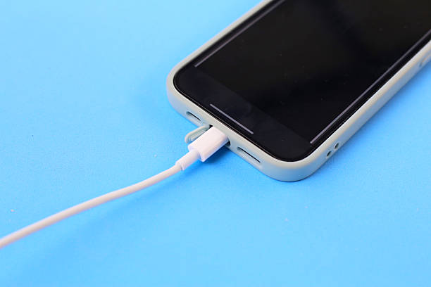 istock Smartphone connected to a white charging cable on a blue background. 2218675950
