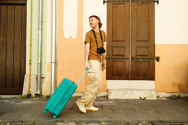 Happy man with travel bag looking for location on map while walking through city.