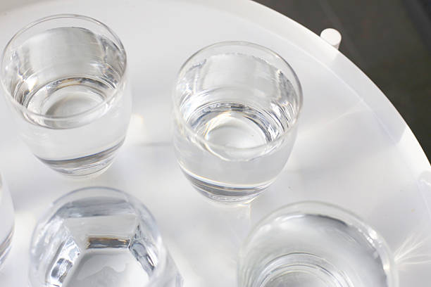 istock Clear drinking water in various glass cups arranged on a white surface. 2218677103