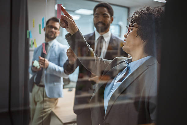 istock Coworkers brainstorming and planning use sticky notes on glass wall 2218677493