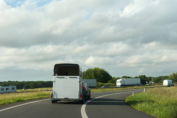 istock Car towing horse trailer on a highway under cloudy sky 2218678993