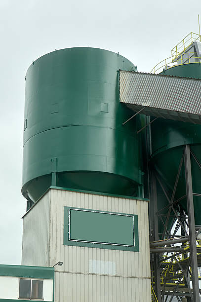 Large green industrial silos dominate the skyline, hinting at the scale of operations within a processing plant